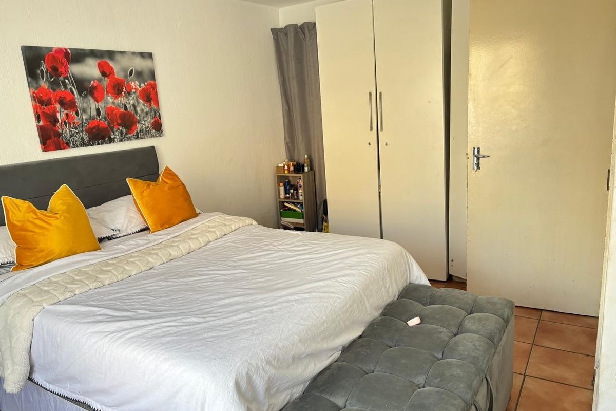 A bedroom featuring tiled flooring and a built-in wardrobe, providing functional storage space within the room.