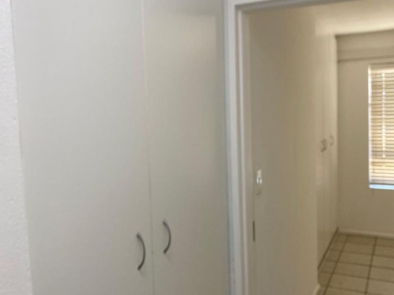 A functional hallway featuring built-in storage cupboards and neutral tiled flooring, providing a clean and organized transition space within the apartment.