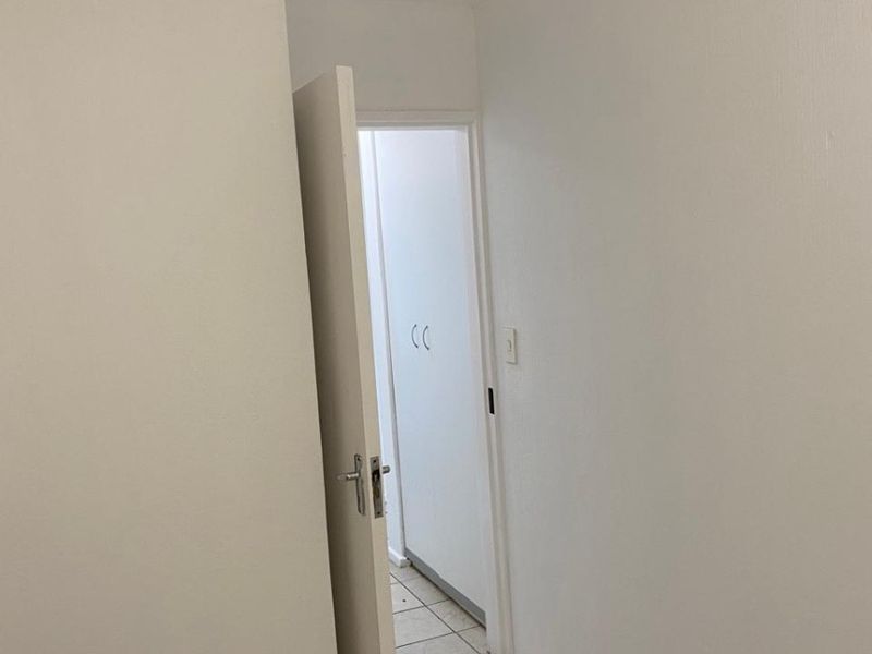 A clean, empty hallway featuring neutral tiled flooring and access to built-in storage cupboards.