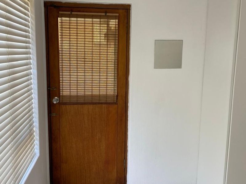 A clean entry area featuring tiled flooring, a timber door with integrated blinds, and a wall-mounted split-system air conditioning unit.