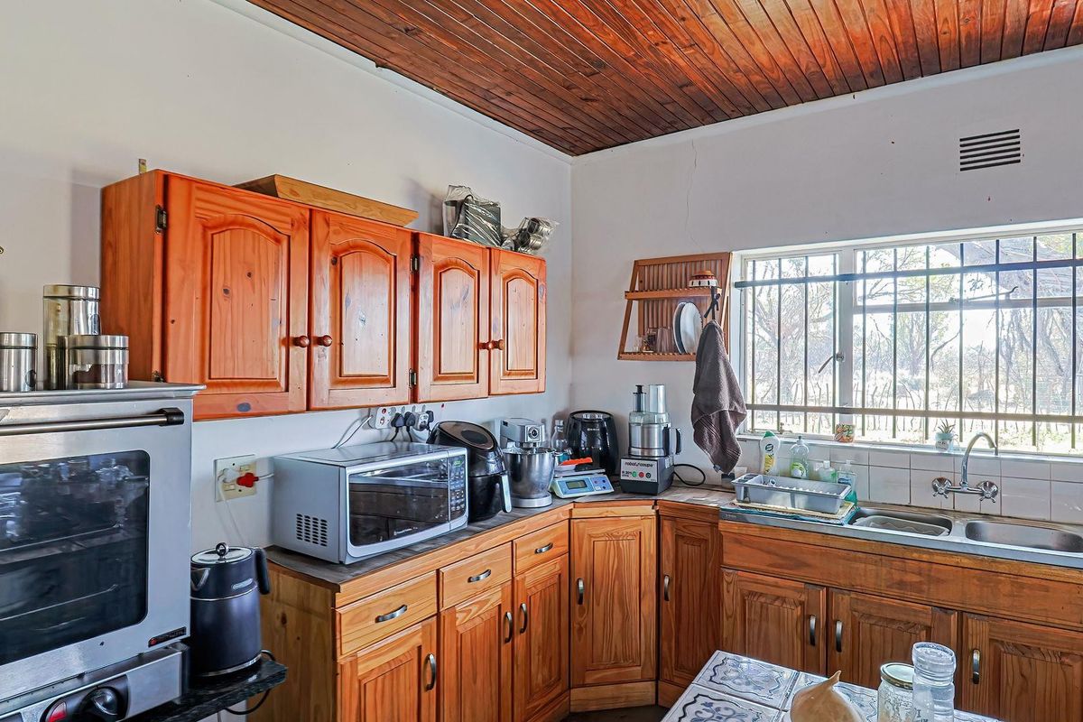 A dated kitchen featuring timber cabinetry, a double basin sink, and a wood-paneled ceiling, offering a functional layout with potential for modern renovation.