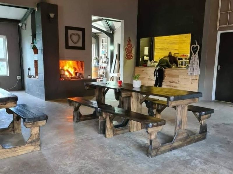 Spacious open-plan area featuring a built-in fireplace, exposed rafters, and a service counter, ideal for a rustic farm-style dining or hospitality space.