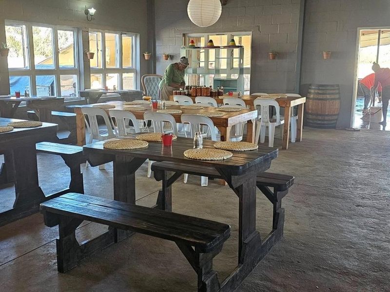 Spacious open-plan dining area featuring exposed blockwork walls, large windows for natural light, and durable concrete flooring, suitable for a farm-style venue.