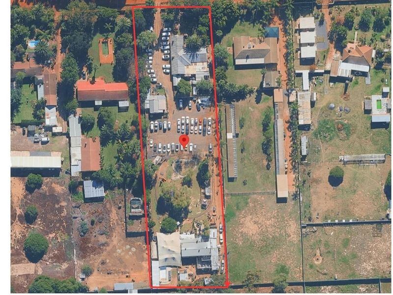 Aerial view of a large farm property featuring multiple outbuildings, extensive parking areas, and established grounds within a defined boundary.