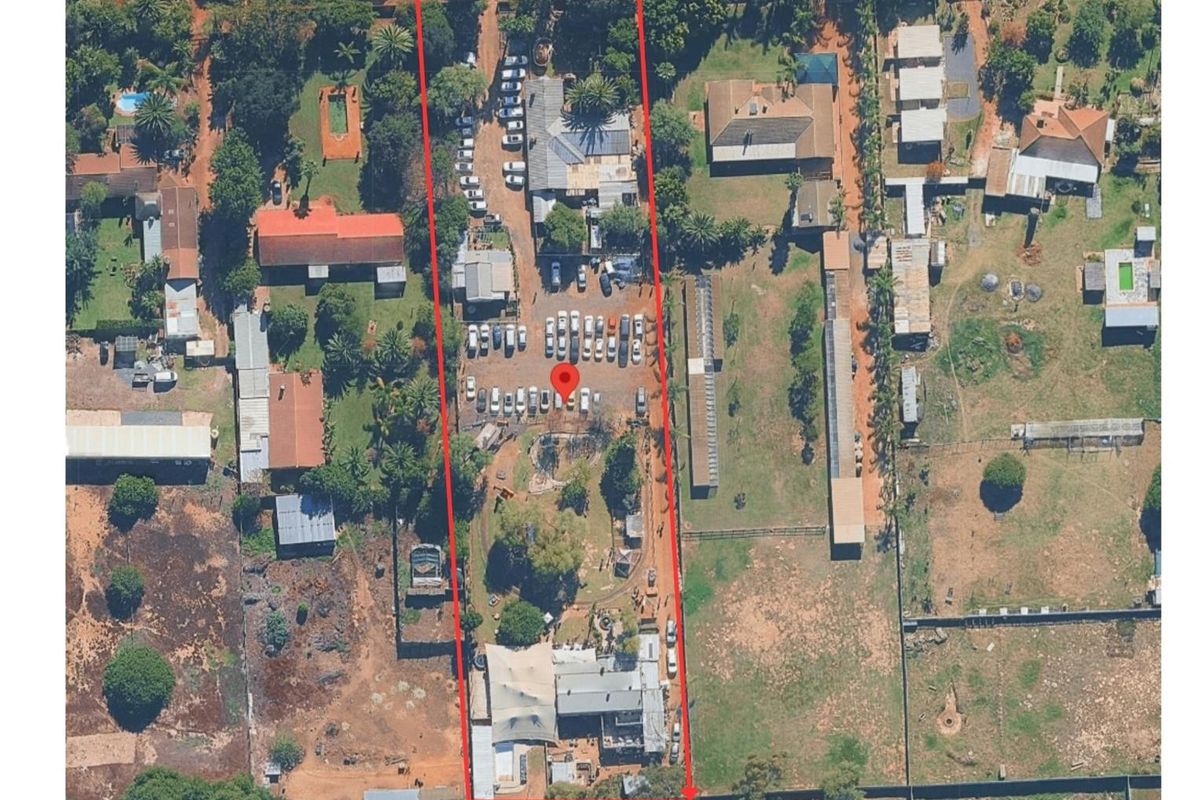 Aerial view of a large farm property featuring multiple outbuildings, extensive parking areas, and established grounds within a defined boundary.
