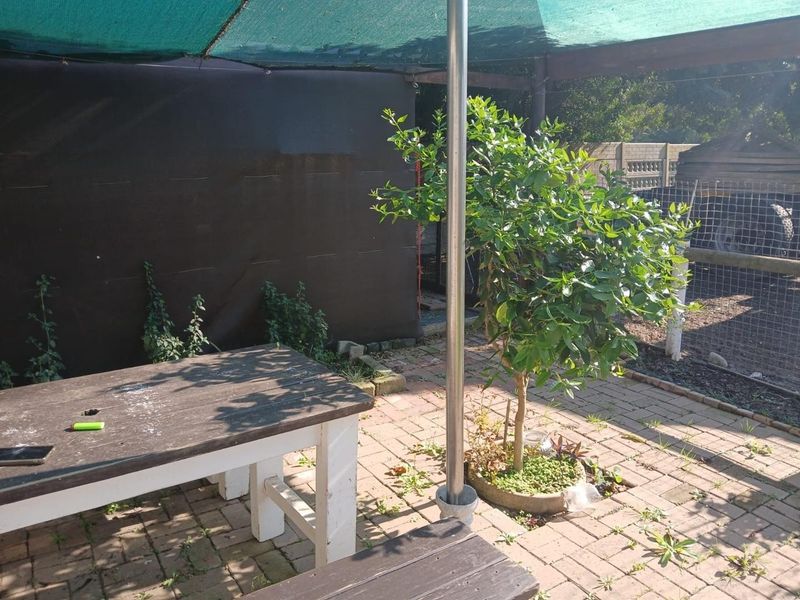 Outdoor patio area featuring paved flooring, a shade cloth canopy structure, and a metal support pole, suitable for outdoor dining or relaxation.