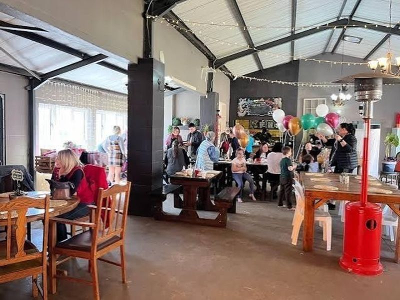 Spacious open-plan venue area featuring exposed steel roof trusses and durable concrete flooring, suitable for events or communal farm gatherings.
