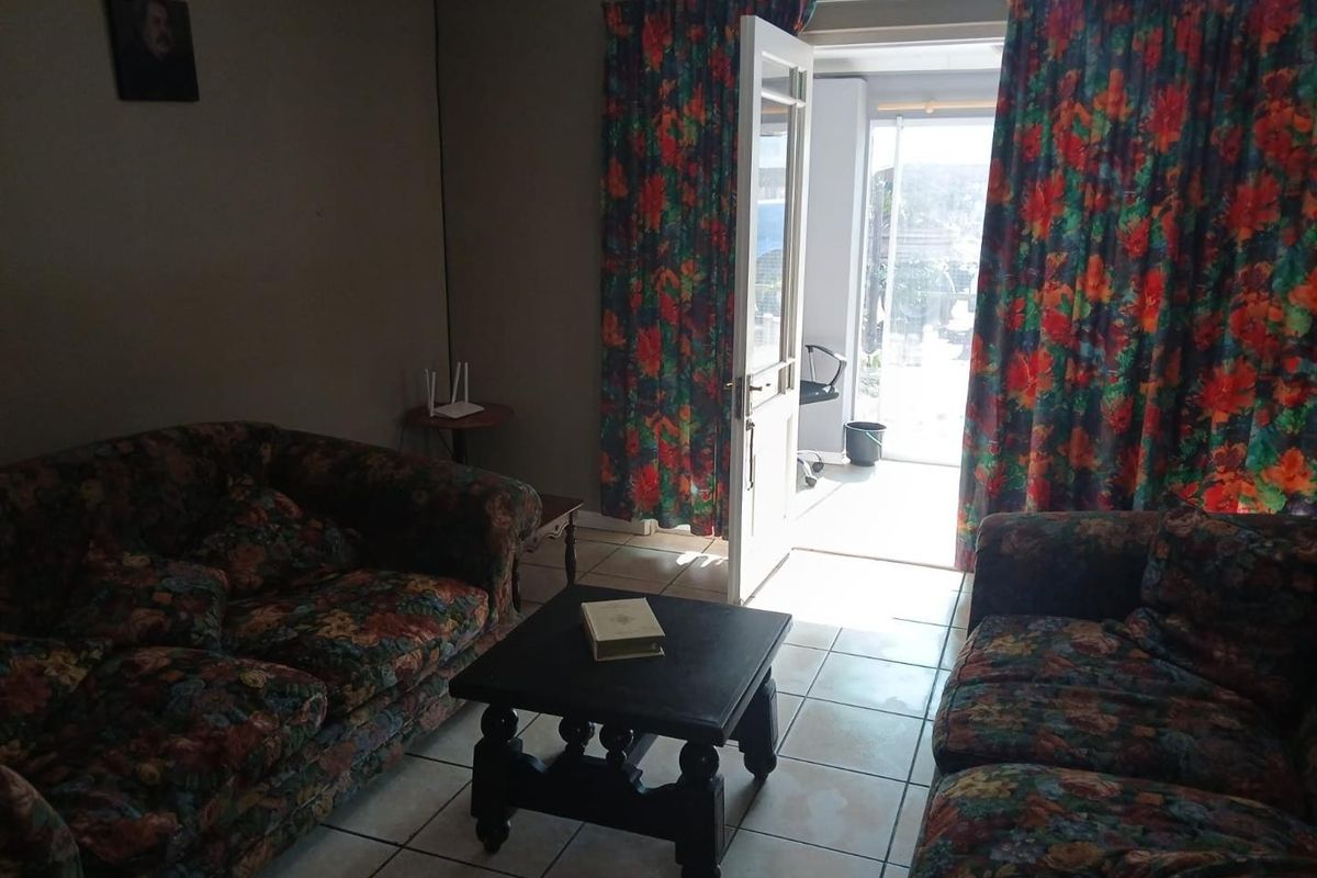 A living room featuring tiled flooring and a glass panel door leading to an outdoor area.
