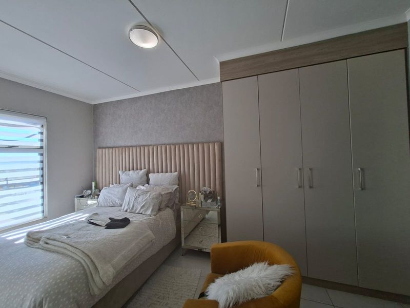 A well-maintained bedroom featuring a large built-in wardrobe, neutral wall finishes, and a modern ceiling light fixture.