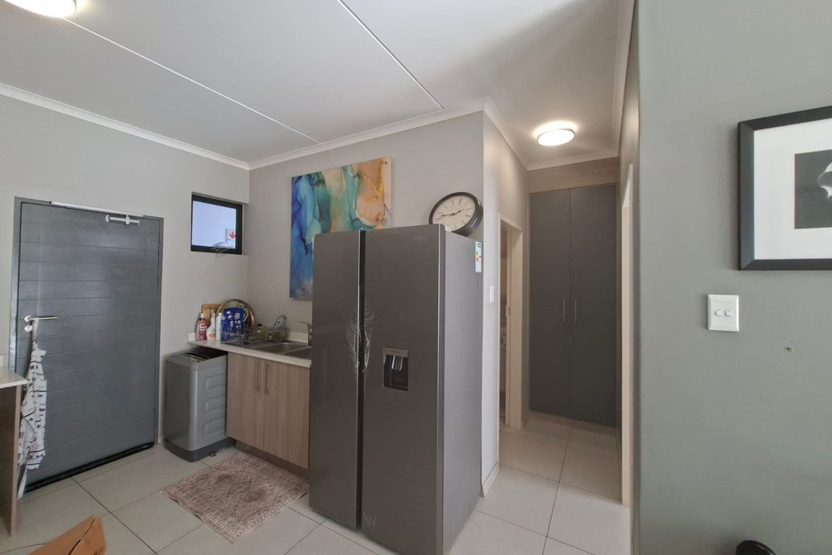 A functional kitchen area featuring tiled flooring, built-in cabinetry, a stainless steel sink, and ample storage space with integrated cupboards.