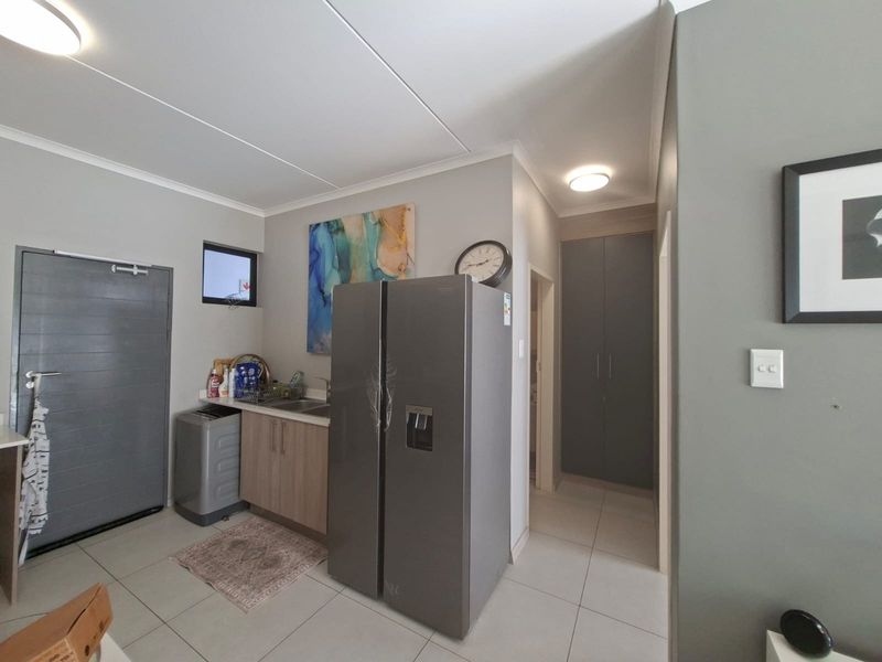 A functional kitchen area featuring tiled flooring, built-in cabinetry, a stainless steel sink, and ample storage space with integrated cupboards.