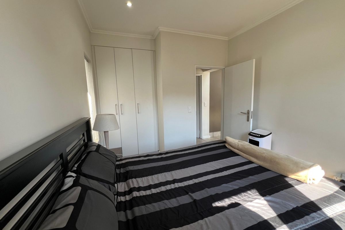 A well-maintained bedroom featuring built-in cupboards, neutral wall finishes, and recessed downlighting, providing a clean and functional living space.