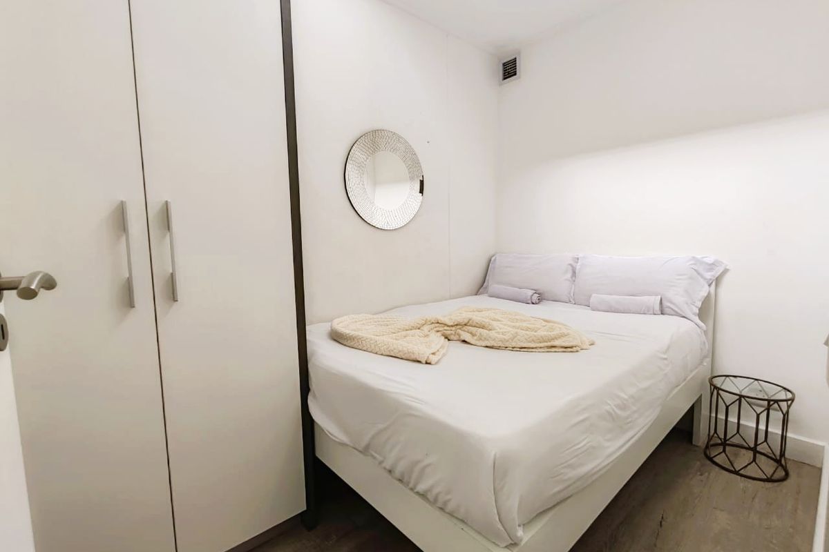 A compact bedroom featuring a built-in wardrobe and neutral finishes, providing a clean and functional sleeping space.