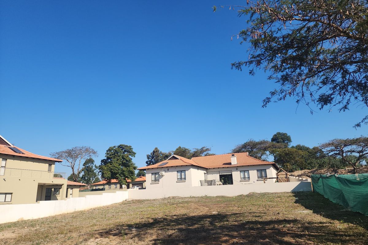 A view of the rear elevation of a residential property featuring a tiled roof, plastered walls, and a surrounding boundary wall.