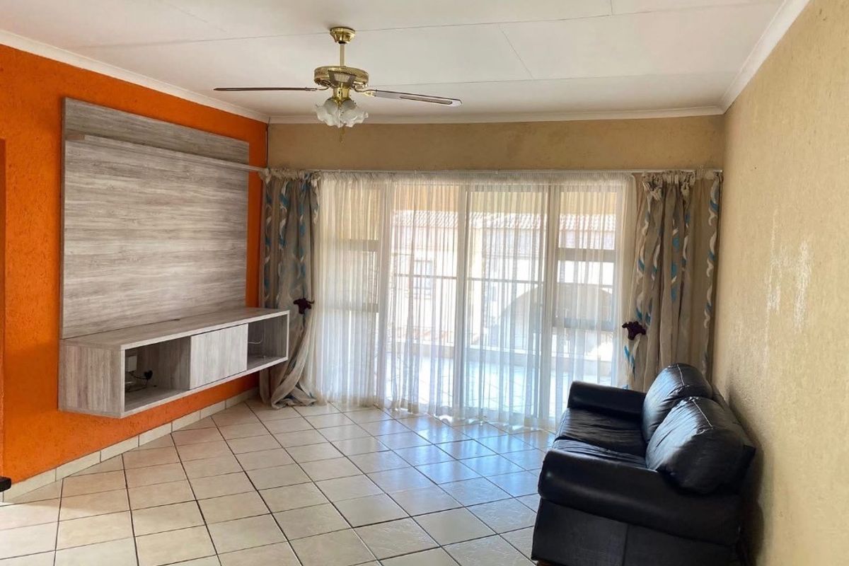 Living room featuring tiled flooring, a ceiling fan, and a built-in media unit, with direct access to an outdoor area through sliding glass doors.