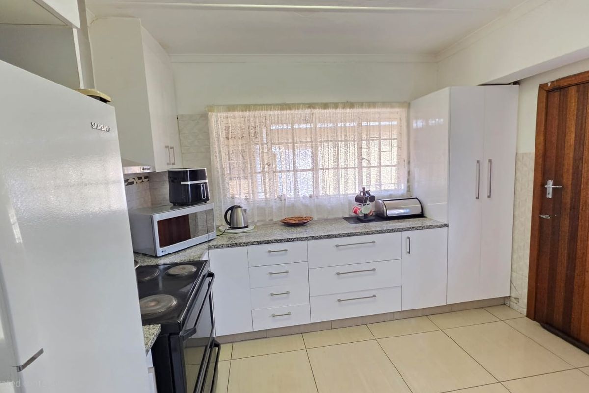 Functional kitchen featuring white cabinetry, granite countertops, tiled flooring, and an integrated stove with extractor fan.