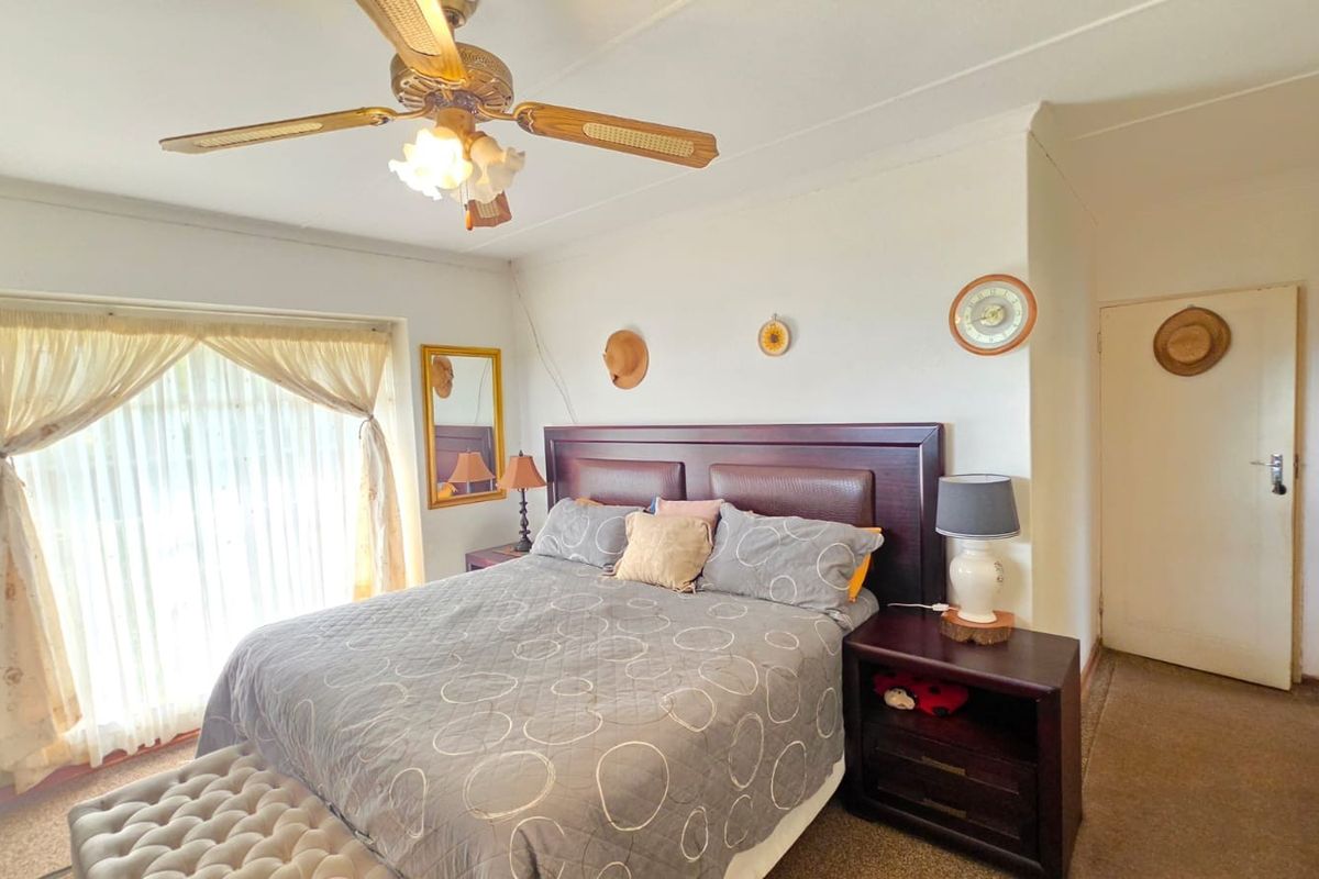 A functional bedroom featuring a ceiling fan and built-in storage, offering a comfortable space with potential for cosmetic updates.
