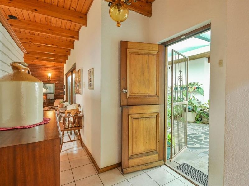 Entrance area featuring a classic dutch door, exposed timber ceiling beams, and tiled flooring, leading out to a covered patio space.