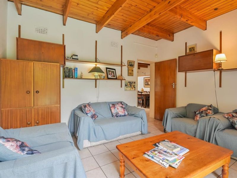 Living room featuring exposed timber beam ceilings, ceramic tiled flooring, and built-in wall shelving units.