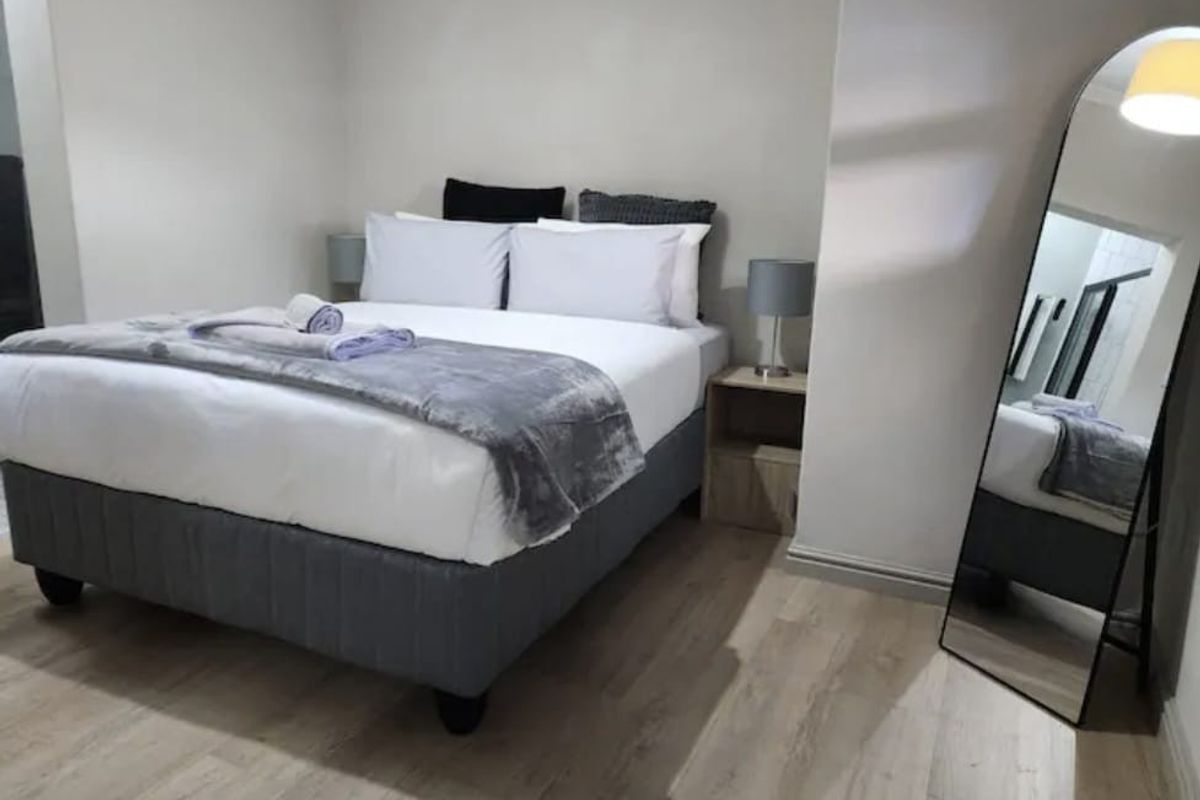 A well-maintained bedroom featuring light-toned laminate flooring and neutral wall finishes, providing a clean and comfortable living space.