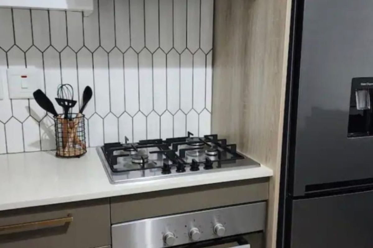 Modern kitchen featuring a gas hob, built-in oven, stainless steel extractor fan, and stylish tiled backsplash with ample cabinetry.