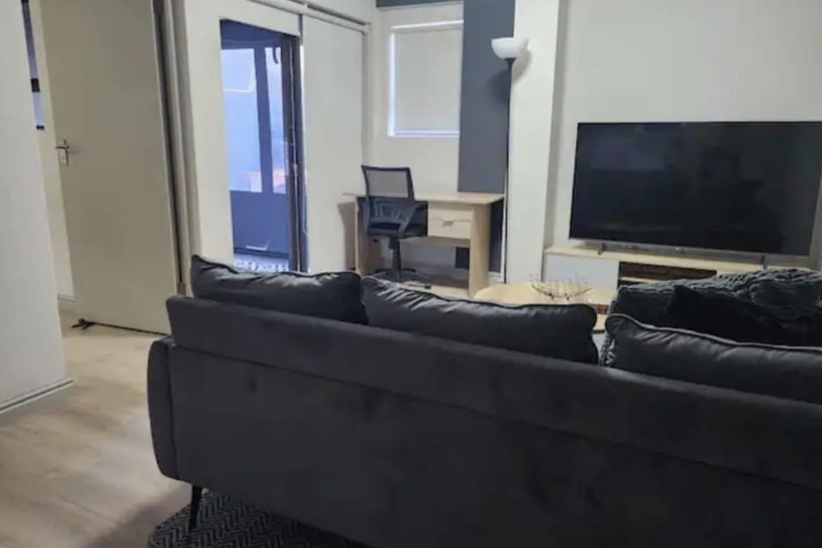 A well-maintained living room featuring laminate flooring, neutral walls with a feature accent, and access to an outdoor area.