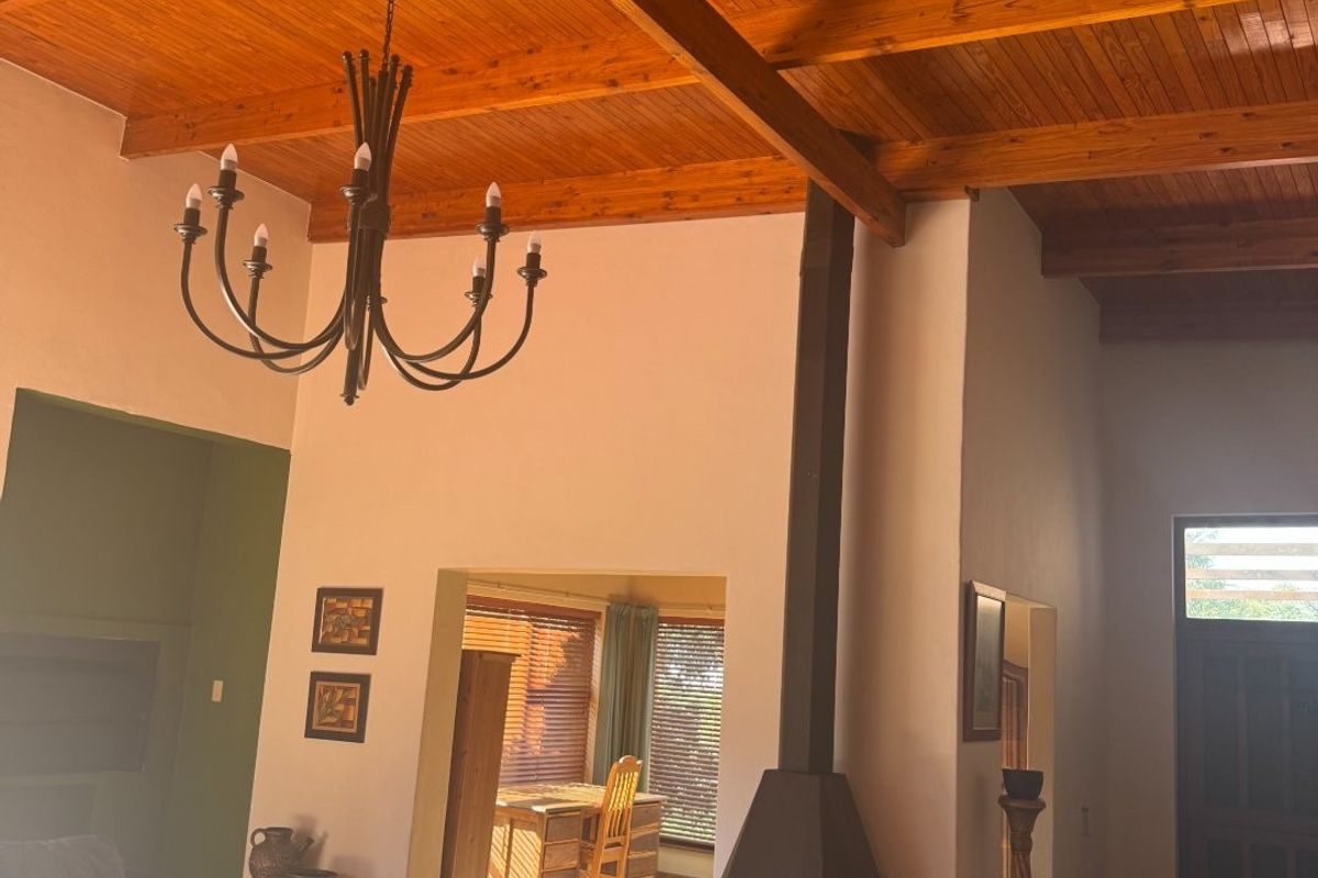 Spacious living room featuring a high exposed timber beam ceiling, a central freestanding metal fireplace, and tiled flooring with access to an adjacent dining area.