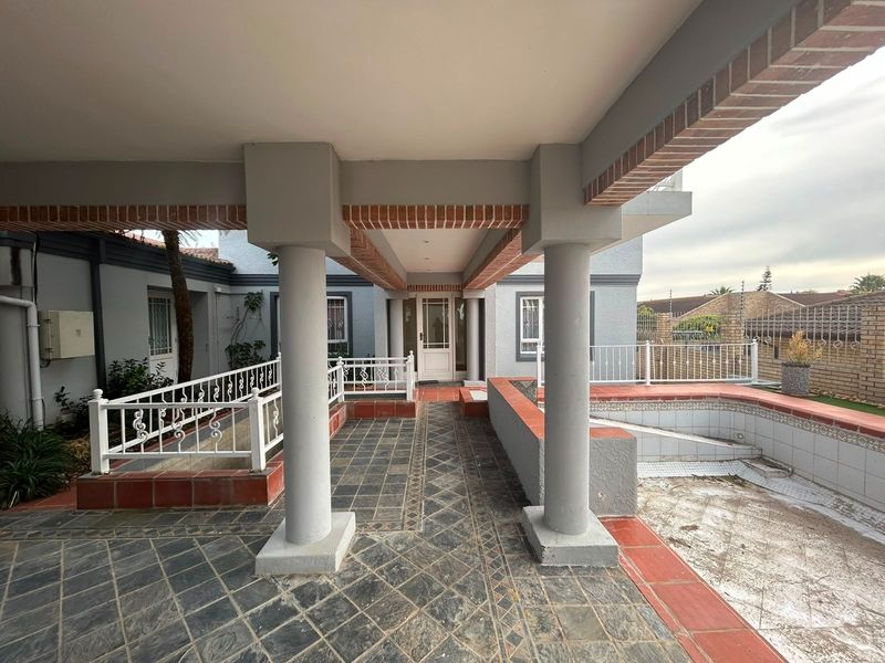 A covered outdoor patio area featuring stone tile flooring, brick accents, and wrought iron railings, providing a sheltered entrance to the lodge.