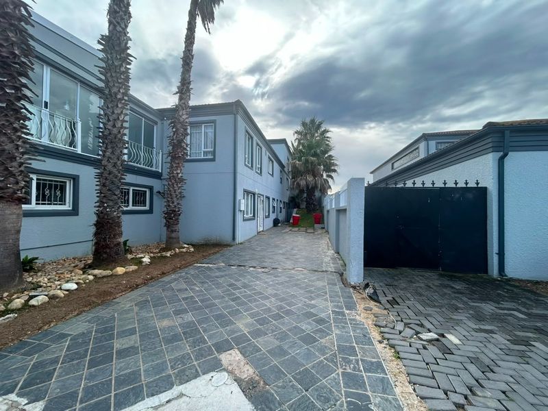 Front exterior view of the lodge featuring a paved driveway, perimeter wall, and metal security gate leading to the multi-story building.