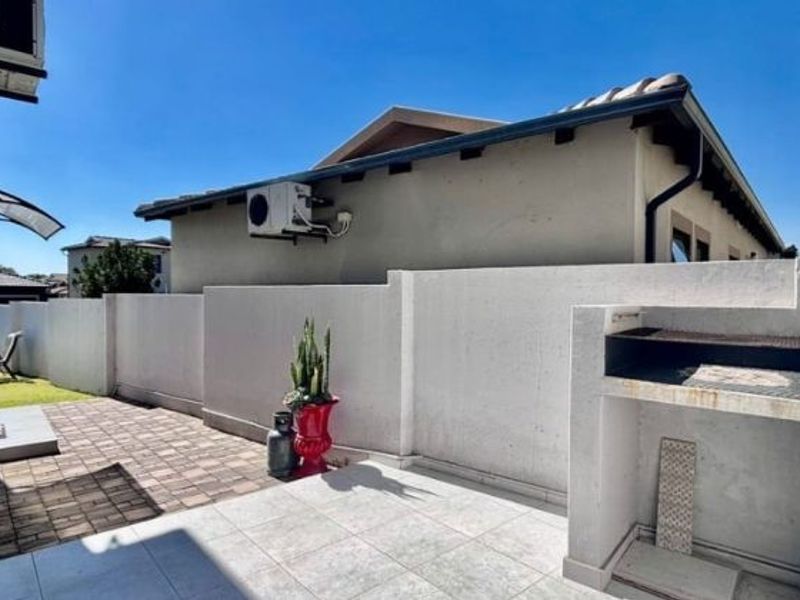 Outdoor patio area featuring a built-in braai, paved flooring, and a boundary wall, providing a functional space for outdoor entertaining.