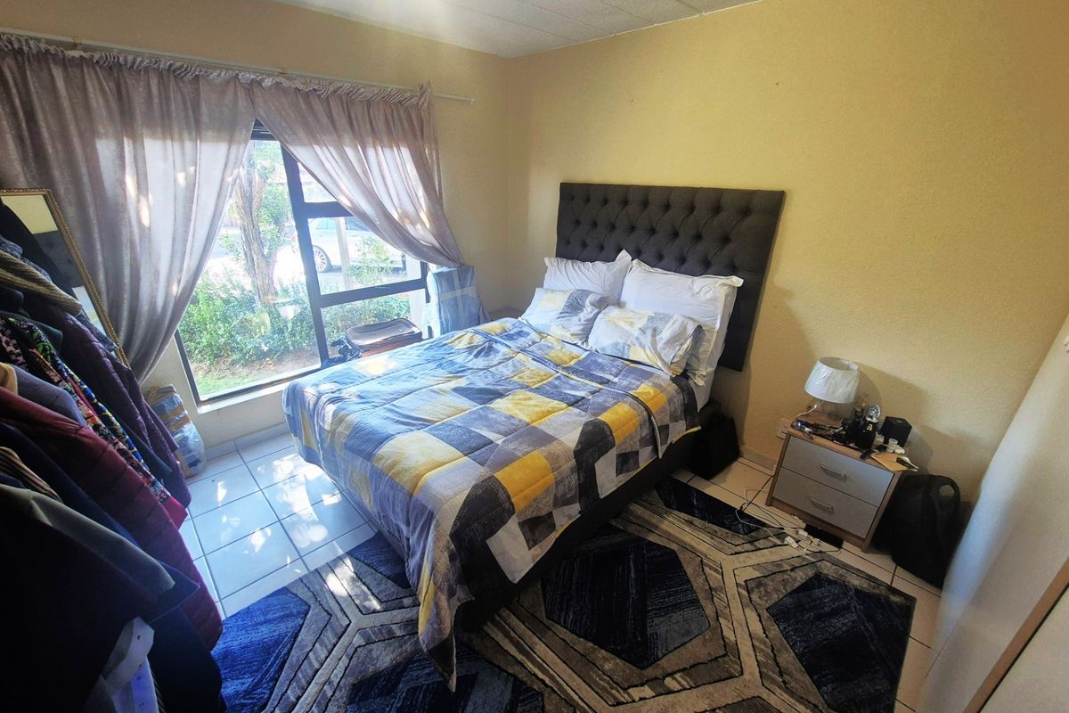 A bedroom featuring tiled flooring and a large window providing natural light.