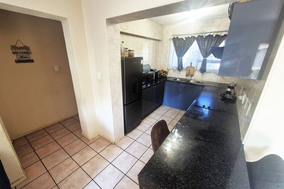 A functional kitchen featuring dark cabinetry, granite countertops, a double sink, and tiled finishes, offering a practical layout for daily meal preparation.
