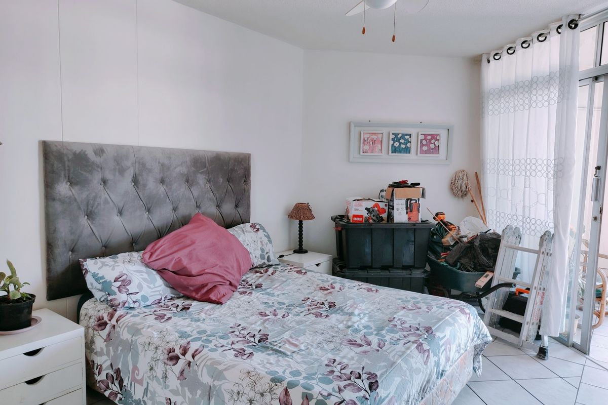 A bedroom featuring tiled flooring, a ceiling fan, and a sliding glass door providing access to an outdoor area.