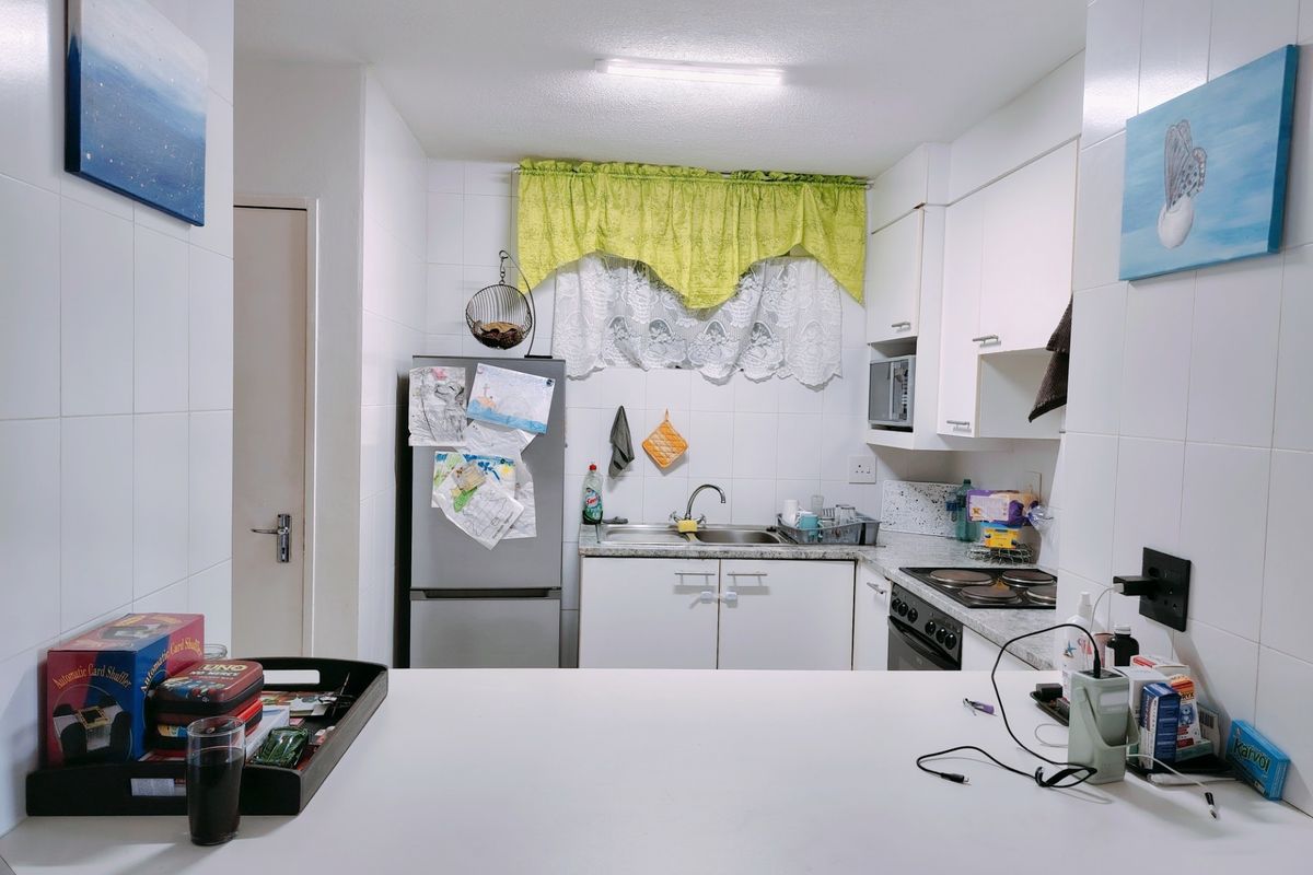 A functional kitchen featuring white cabinetry, a tiled splashback, built-in oven and hob, and a convenient breakfast counter for casual dining.