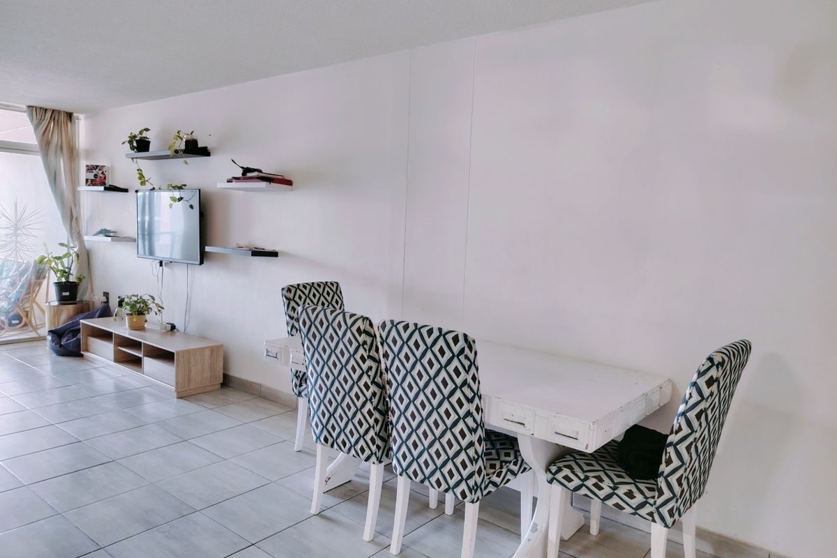 Open plan living and dining area featuring neutral tiled flooring and access to an outdoor balcony through a sliding glass door.