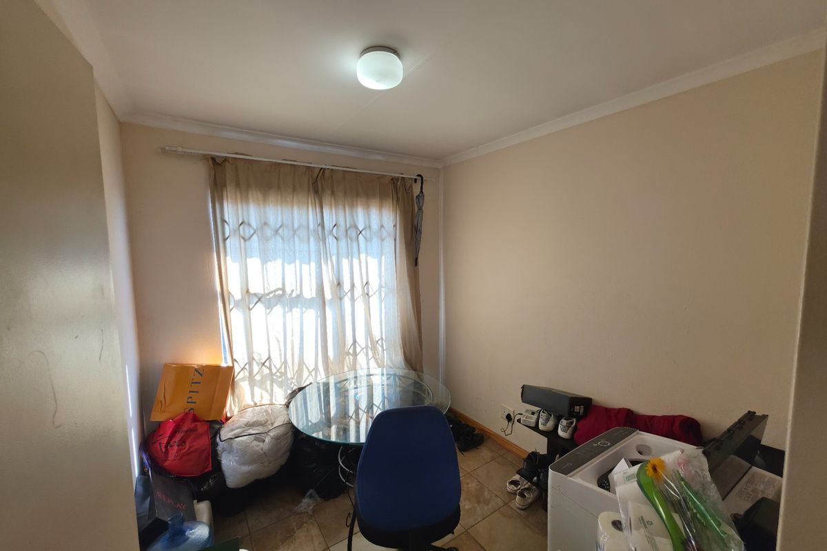 A compact bedroom featuring tiled flooring and a security gate over the window, providing a functional space ready for personalization.