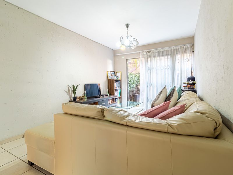 A living room featuring tiled flooring and a sliding glass door with a security gate, providing access to the outdoor area.