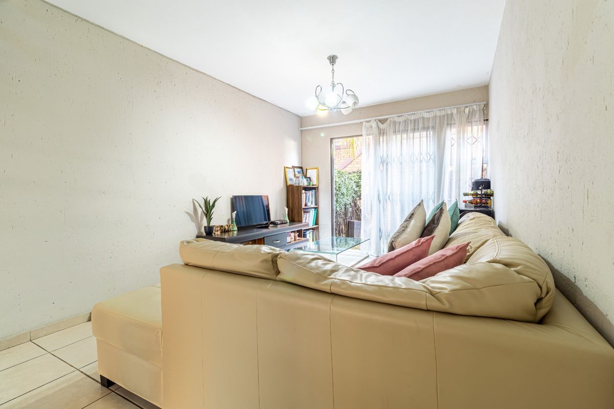 A living room featuring tiled flooring and a sliding glass door with a security gate, providing access to the outdoor area.