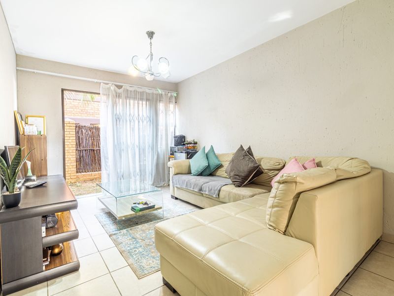 A living room featuring tiled flooring and a sliding glass door with security gate providing access to the exterior.