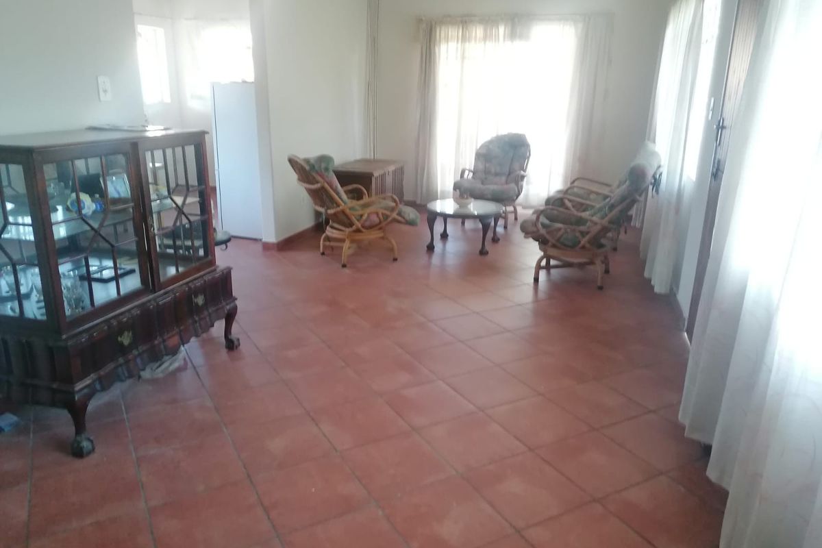 Spacious living area featuring terracotta floor tiles and large sliding glass doors providing natural light.