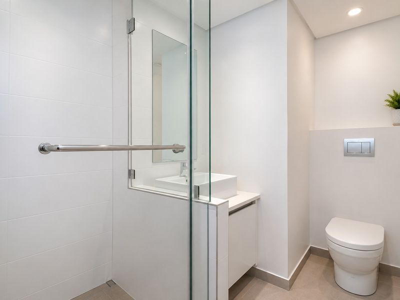 Modern bathroom featuring a glass-enclosed shower, wall-mounted toilet, and a sleek vanity with a vessel sink.