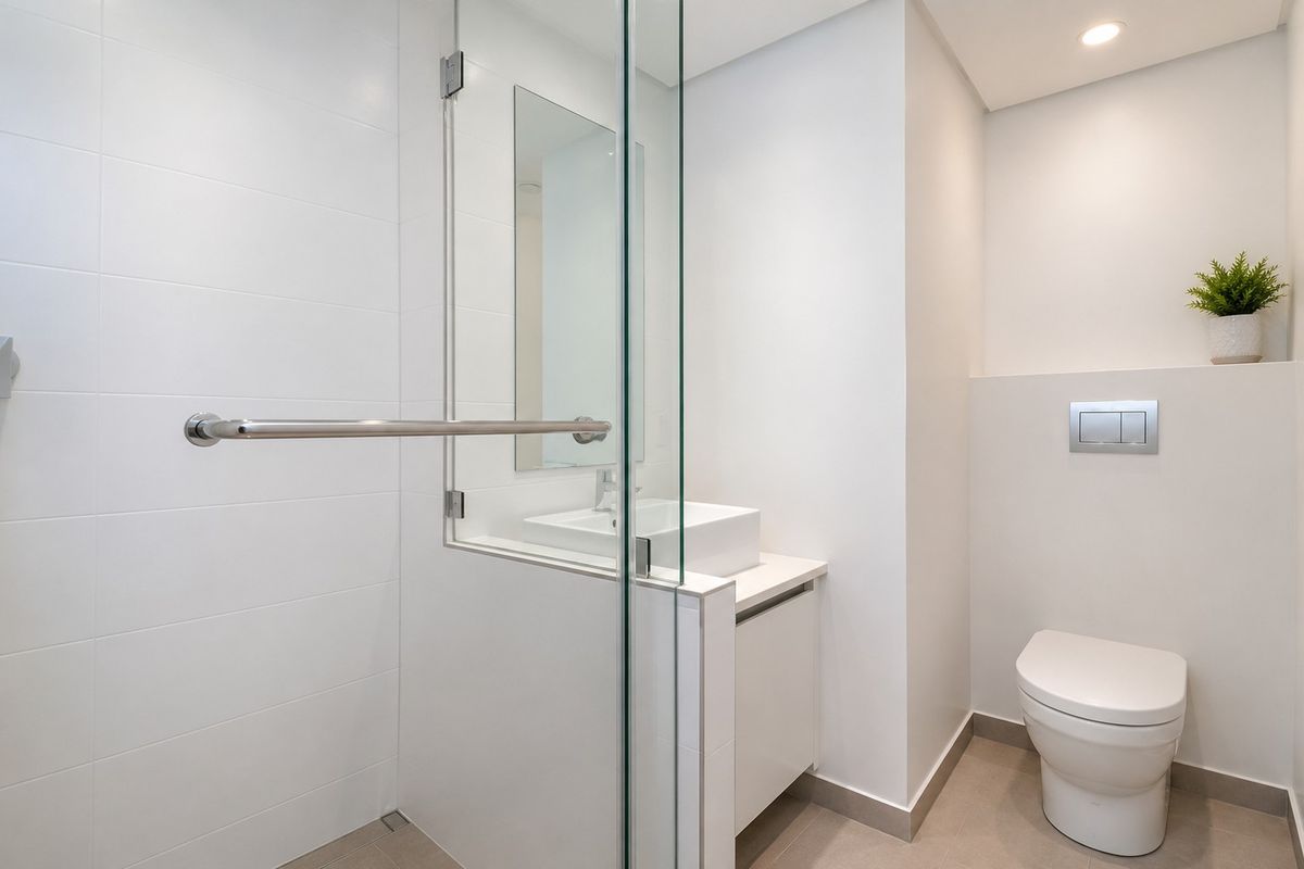 Modern bathroom featuring a glass-enclosed shower, wall-mounted toilet, and a sleek vanity with a vessel sink.