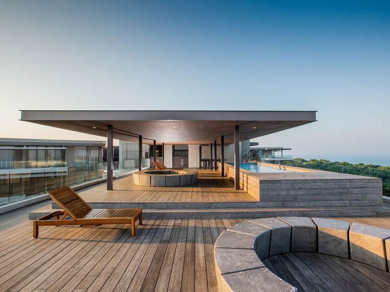 Expansive rooftop terrace featuring a swimming pool, timber decking, and built-in stone seating areas with panoramic views.