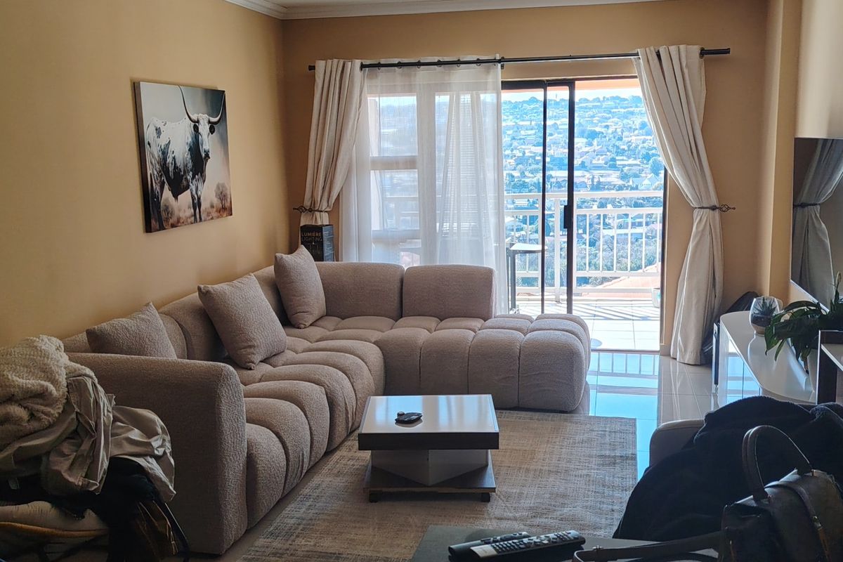 A comfortable living room featuring tiled flooring and a large sliding glass door that opens onto a balcony with expansive views.