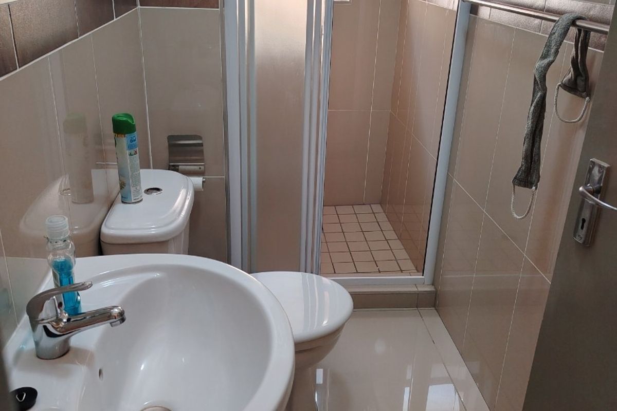 A functional bathroom featuring a pedestal basin, toilet, and a separate shower enclosure with tiled finishes throughout.