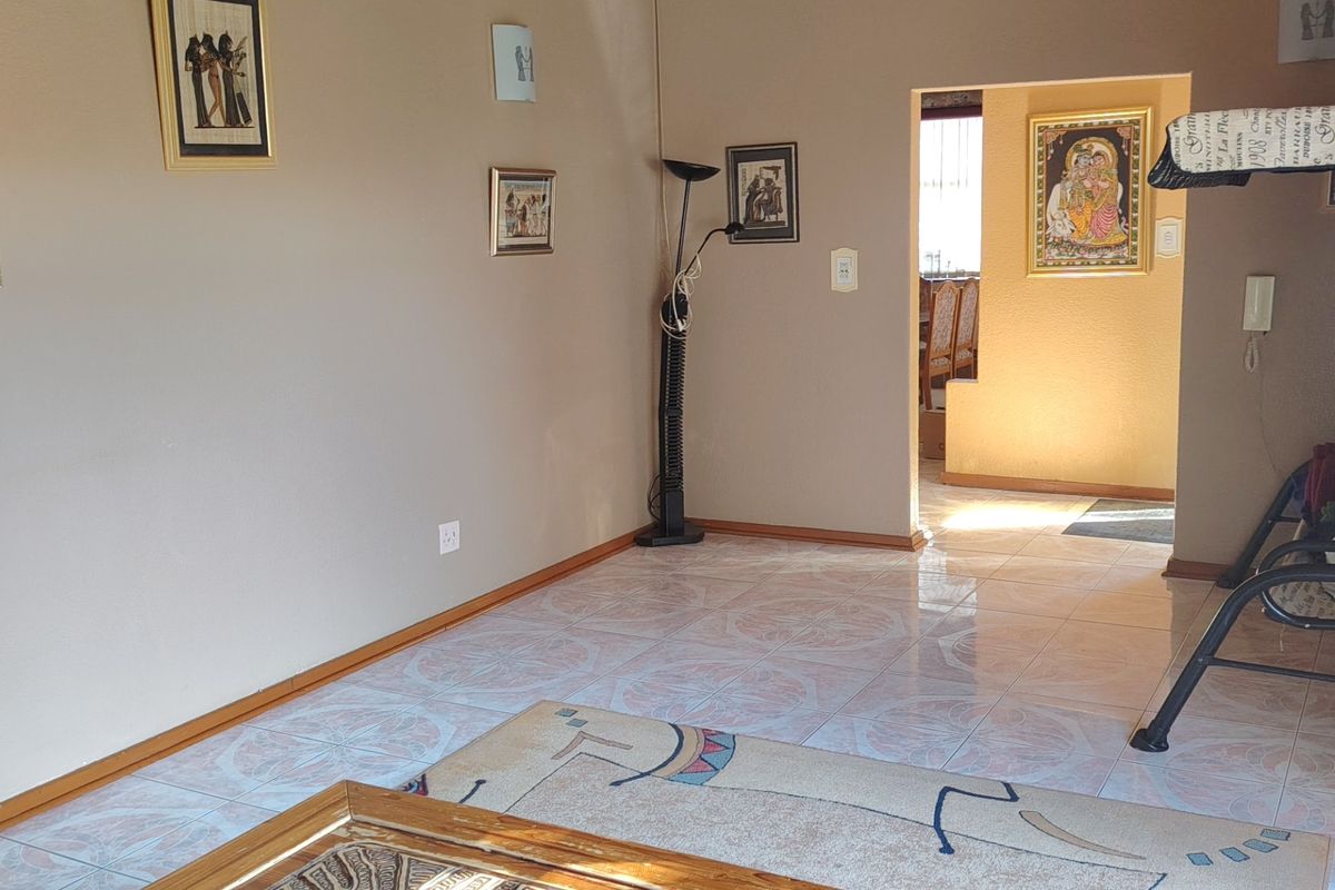 A living room area featuring ceramic floor tiles and neutral wall finishes, with an open transition leading into an adjacent room.