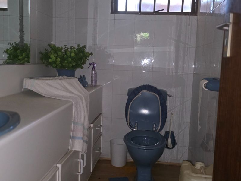 A dated bathroom featuring blue sanitaryware, a built-in vanity unit, and tiled walls, requiring modernization to improve its aesthetic appeal.