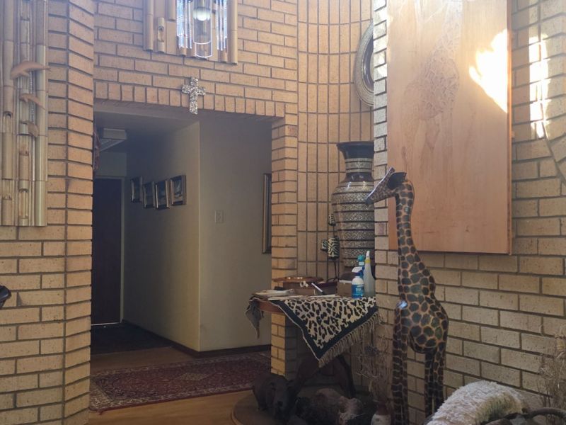 Entrance foyer featuring distinctive exposed brick walls, an arched architectural opening, and warm hardwood flooring.