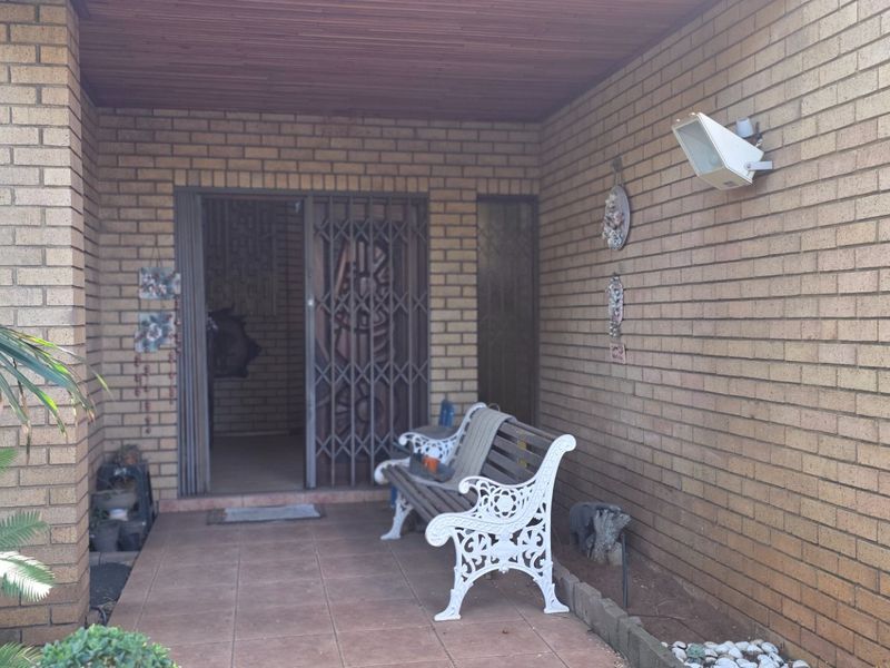 A covered patio area featuring brick walls, tiled flooring, and a secure entrance gate, providing a functional outdoor transition space.