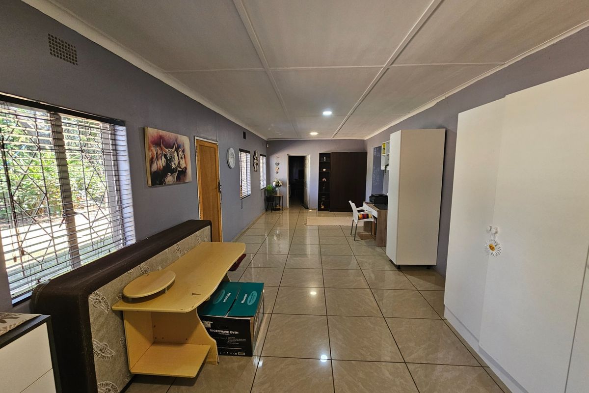 Spacious bedroom featuring large format floor tiles, built-in storage cupboards, and security bars on the windows, offering a functional and well-lit living space.